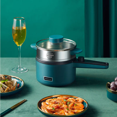 Homeshinex mini electric cooking pot in teal with glass lid surrounded by seafood dishes and a glass of white wine