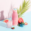 Homeshinex portable electric juicer blender in pink next to a glass of pink juice with fruit and greenery