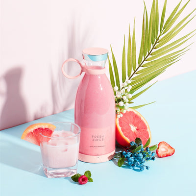 Homeshinex portable electric juicer blender in pink next to a glass of pink juice with fruit and greenery