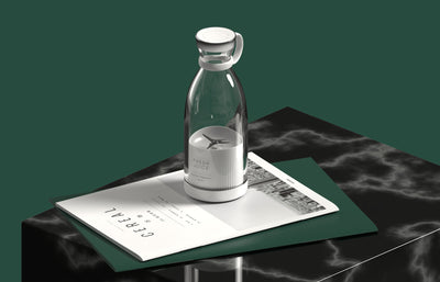 Homeshinex portable electric juicer blender in clear design placed on magazine on black marble table