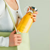 Person placing Homeshinex portable electric juicer blender filled with orange juice into a green handbag
