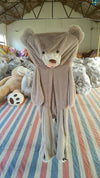 Homeshinex soft leather teddy bear toy in light brown with detailed face and large ears hanging in warehouse