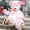 Large soft leather teddy bear toy in pink sitting outdoors next to a woman on stone steps