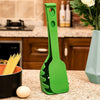 Green versatile kitchen spoon for pasta and eggs standing on kitchen counter next to uncooked spaghetti and an egg